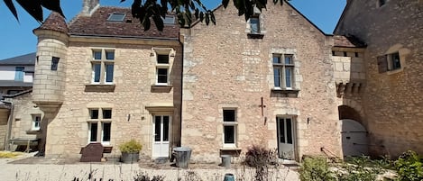 A stone building with multiple windows, a door, and a small balcony.