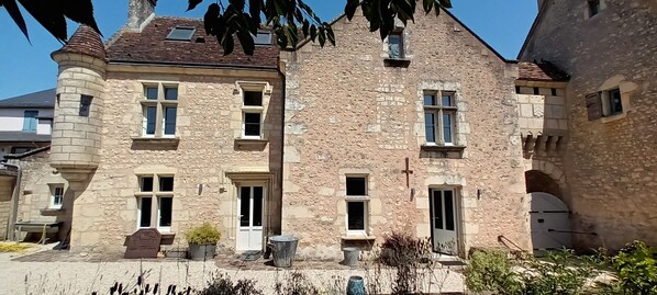 A stone building with multiple windows, a door, and a small balcony.