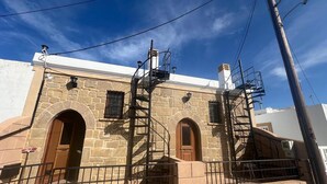 Edifici de pedra amb dues portes en arc i una escala espirallada que condueix a un segon pis.