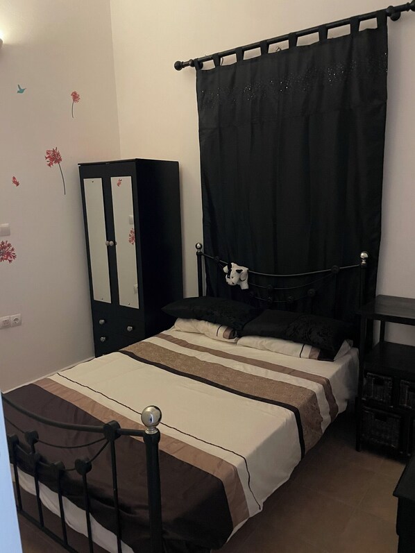 A bedroom with a bed, a wardrobe, a nightstand, and a black canopy. - Rustic 1 Bd Stone Apt in Malonas Rodos (Rhodes)