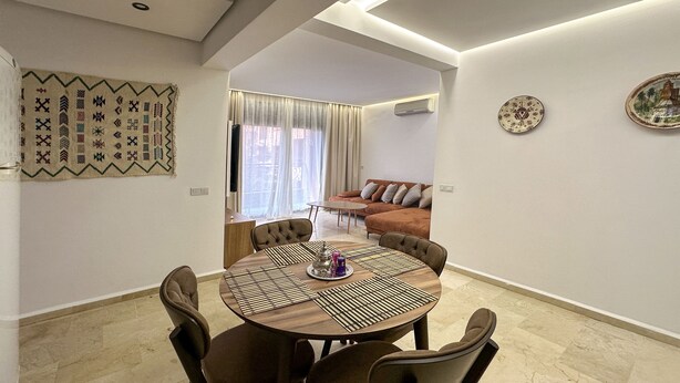 A dining area with a round table, chairs, and a decorative wall hanging.