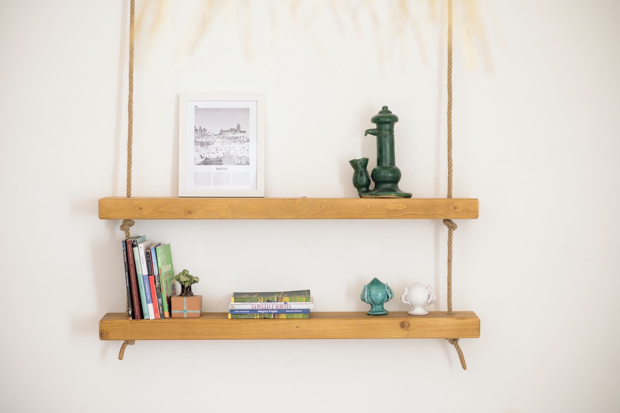 Two wooden shelves with books, a framed picture, a green pump, and a small white figurine.