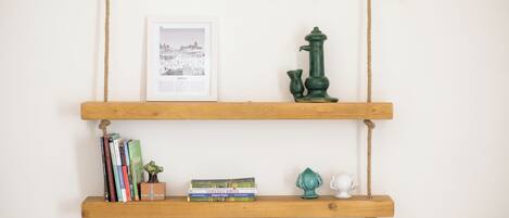 Two wooden shelves with books, a framed picture, a green pump, and a small white figurine.