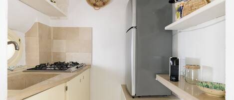 A compact kitchen with a gas stove, a stainless steel refrigerator, and a small countertop.