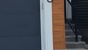 A modern house with a dark garage door, a wooden panel accent, and a black metal staircase. - Modern & Cozy 2 Bedroom Apartment in Seton, Calgary: Haven Away from Home! (Calgary)