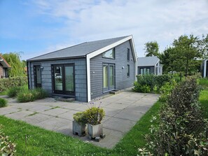Une maison moderne avec un toit en pente, de grandes fenêtres et une allée pavée.