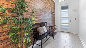 Un intérieur moderne avec un mur en bois, un banc doté d’un coussin et une porte aux panneaux en verre dépoli.