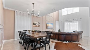 Un espace repas comprenant une grande table et des chaises, un canapé en cuir et un tapis en peau de vache.