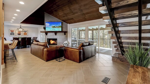 Amplia sala de estar con chimenea, sofás de cuero y un televisor grande.