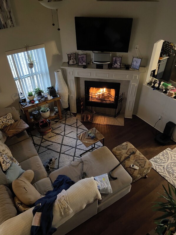 Una sala de estar acogedora con chimenea, un sofá y un televisor montado en la pared.