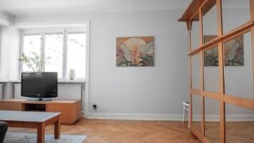 A living room with a TV, wooden furniture, a window, and artwork on the wall.