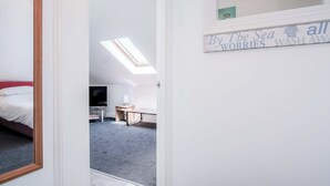 A room with a bed, a desk, a TV, and a skylight.
