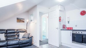 A modern kitchen with white cabinets, a black oven, and a red clock on the wall.