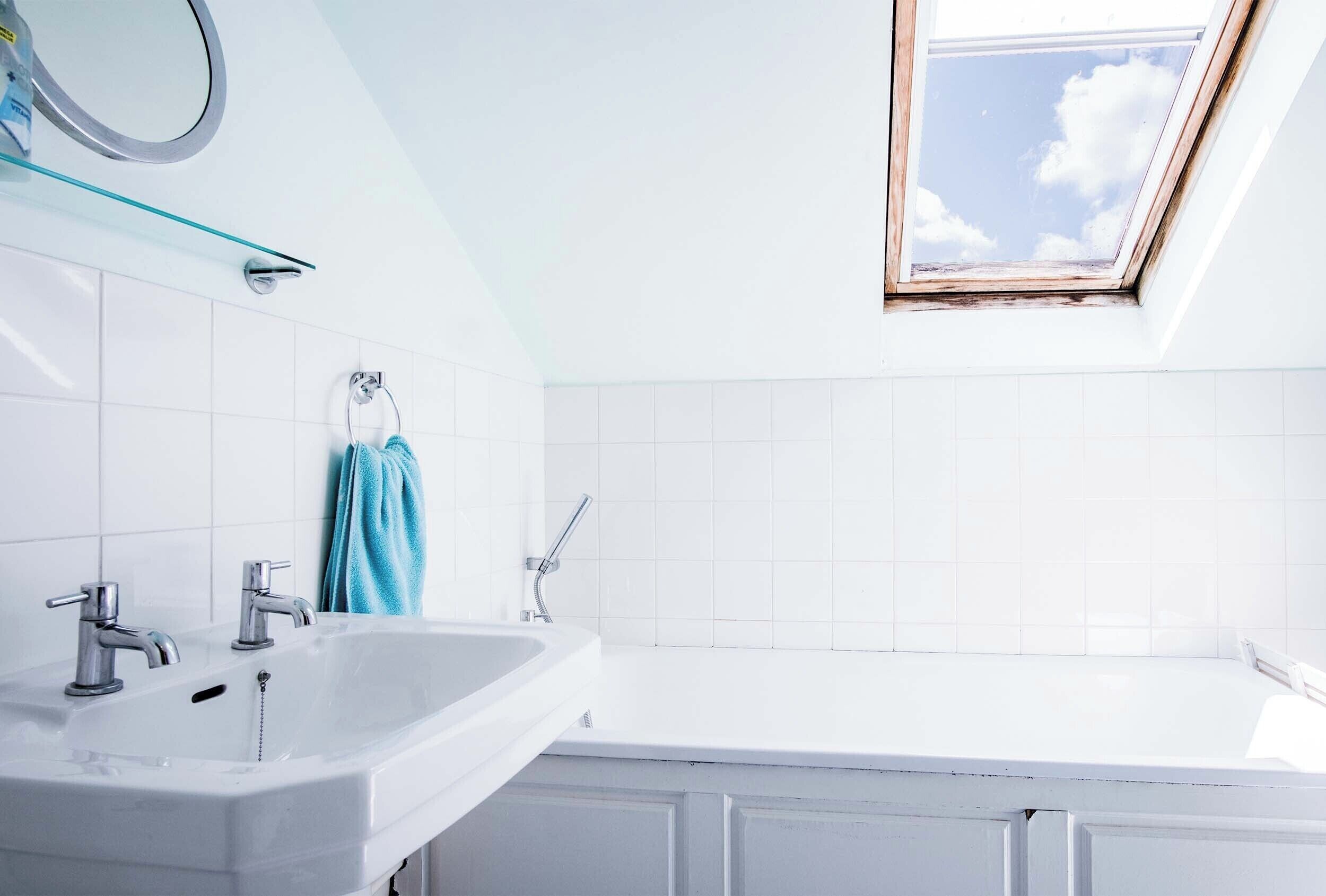 Een moderne badkamer met dakraam, een witte wastafel en een bad.