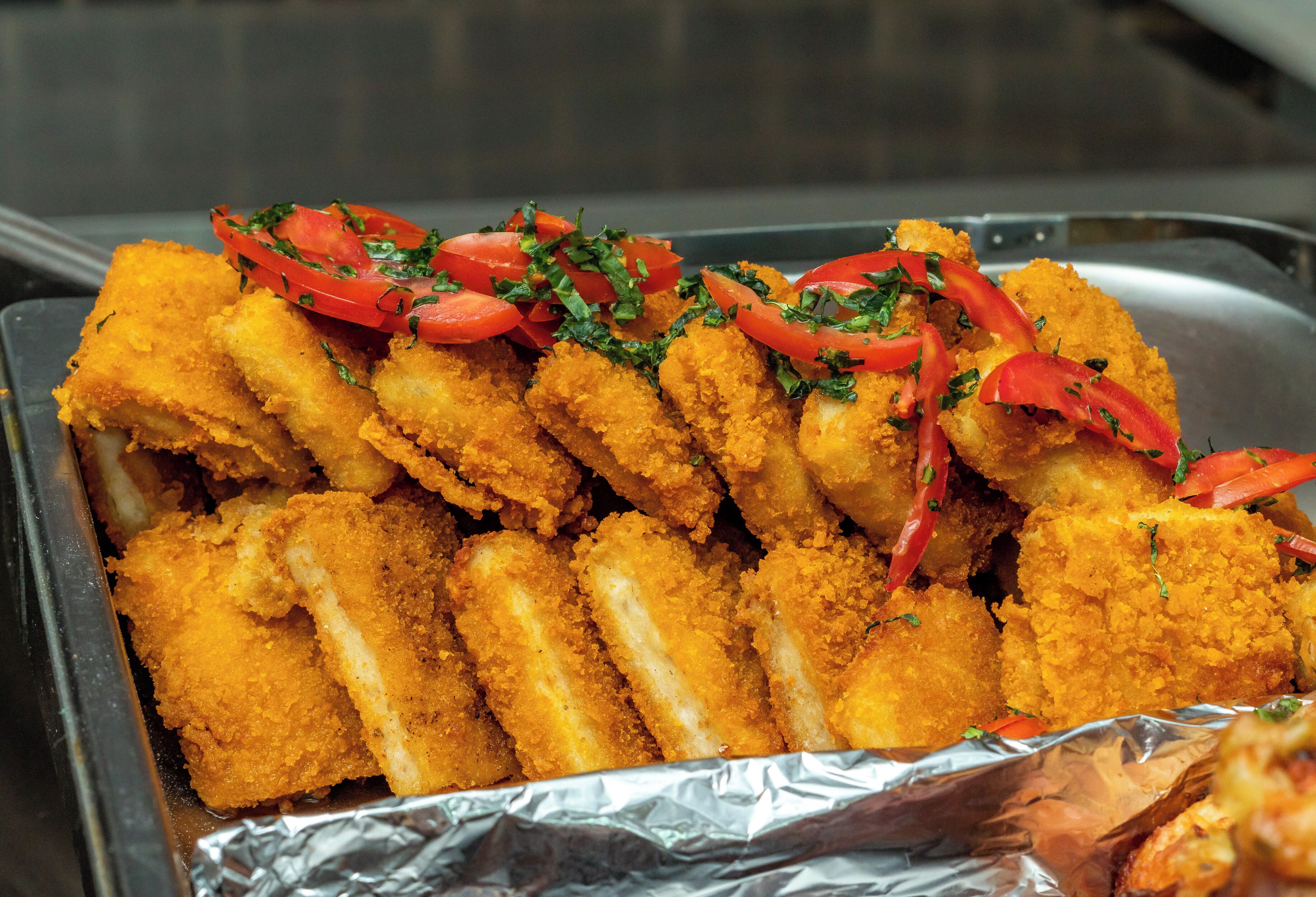 A tray of breaded and fried food items, garnished with tomatoes and herbs.