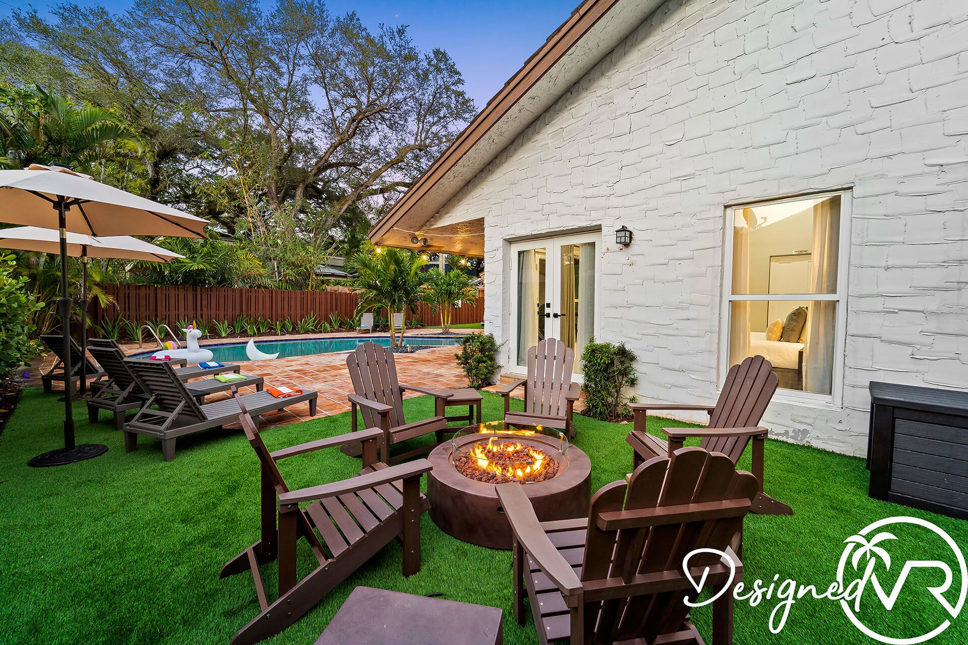 Ein Garten mit Pool, Gartenmöbeln und einer Feuerstelle.