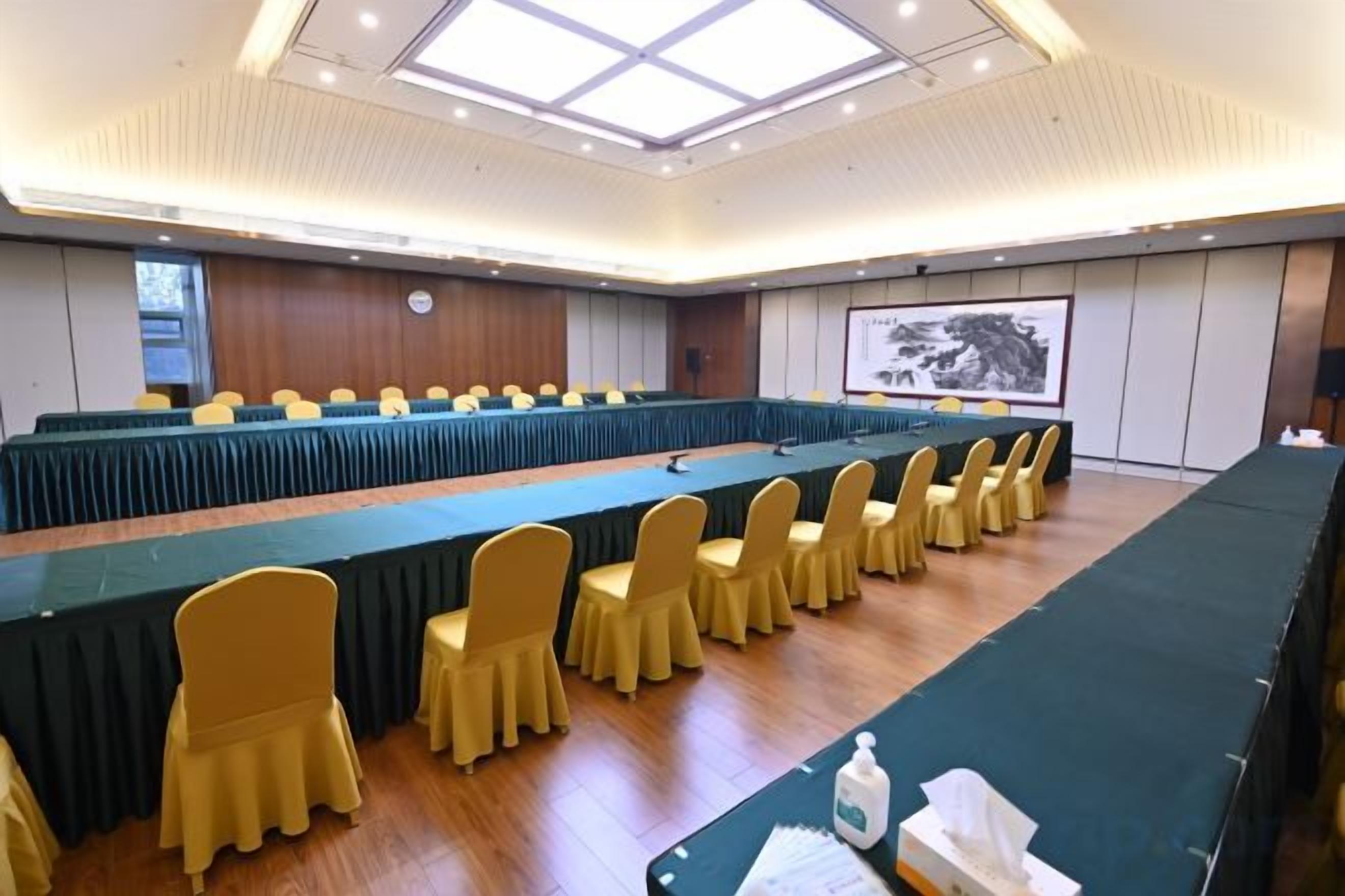 Une salle de conférence avec une longue table, des chaises jaunes et un écran de projection.