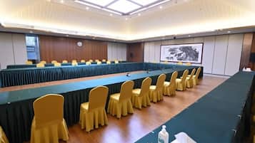 Une salle de conférence avec une longue table, des chaises jaunes et un écran de projection.