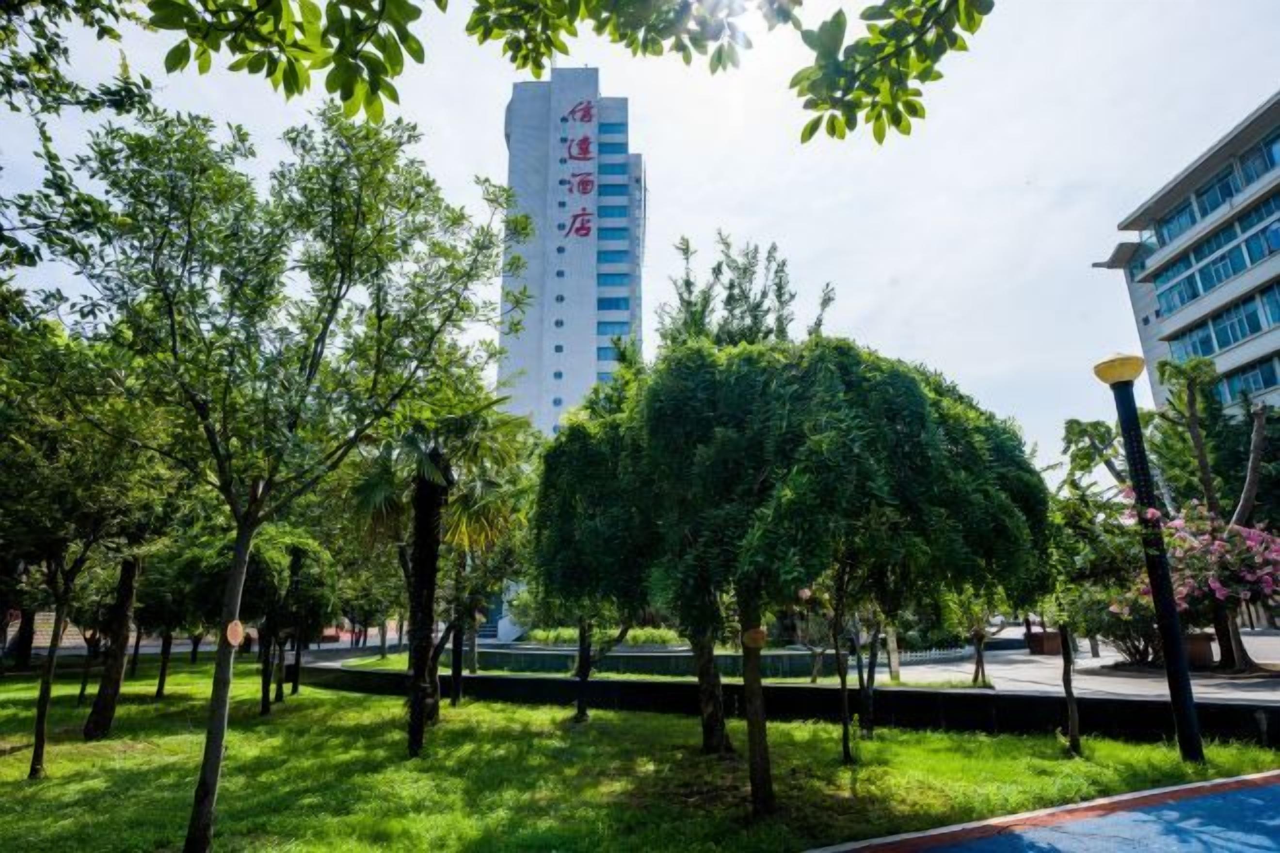 Un edificio de diseño moderno, rodeado de un jardín cuidado con varios árboles y un sendero.