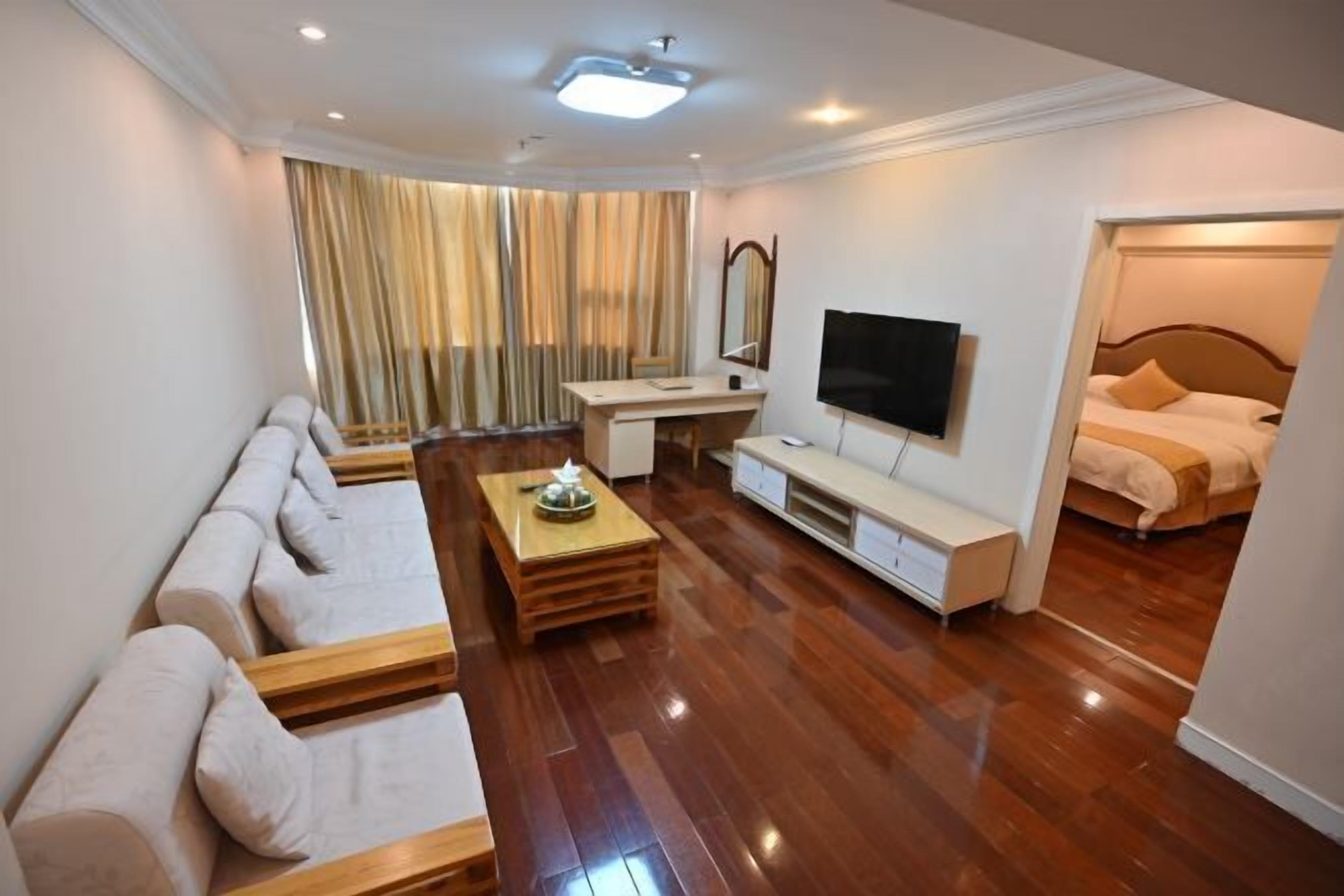 Una habitación de hotel moderna con suelo de madera, un sofá, un televisor, un escritorio y una cama.