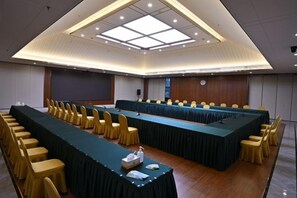 Un salón de conferencias con una larga mesa, sillas y una pantalla de proyector.