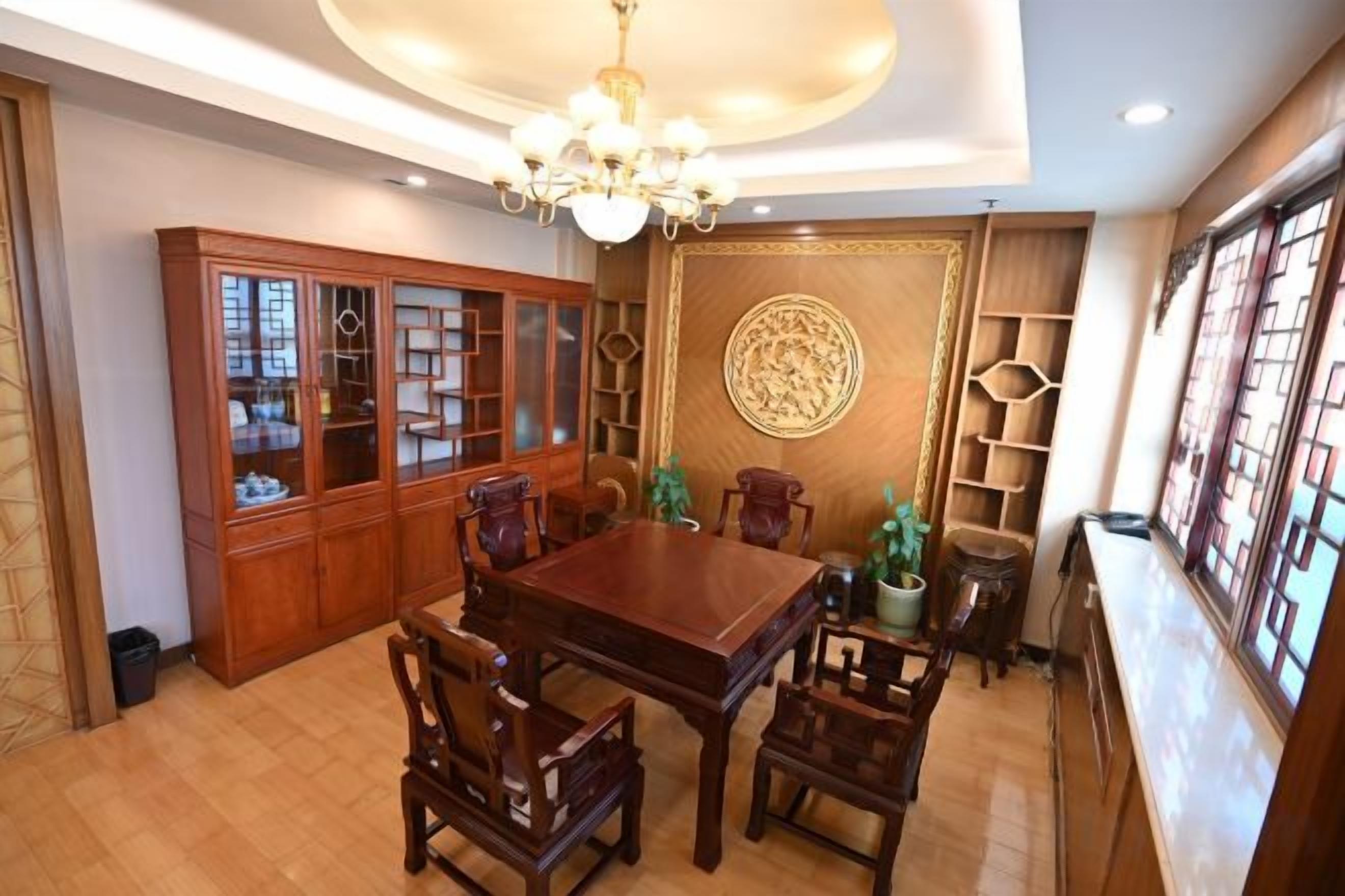 A dining area with a wooden table and chairs, a cabinet with glass doors, and a decorative wall piece.