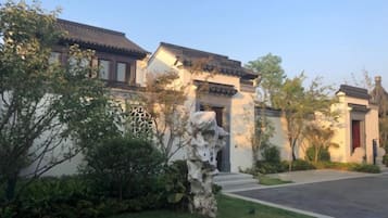 Un bâtiment traditionnel avec un toit en tuiles, un chemin de pierre et une pelouse bien entretenue.