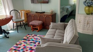 Una habitación acogedora con sofá, sillas, una mesita y un armario.