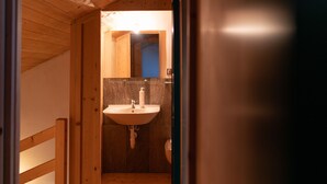 A wooden interior with a bathroom featuring a sink and mirror.