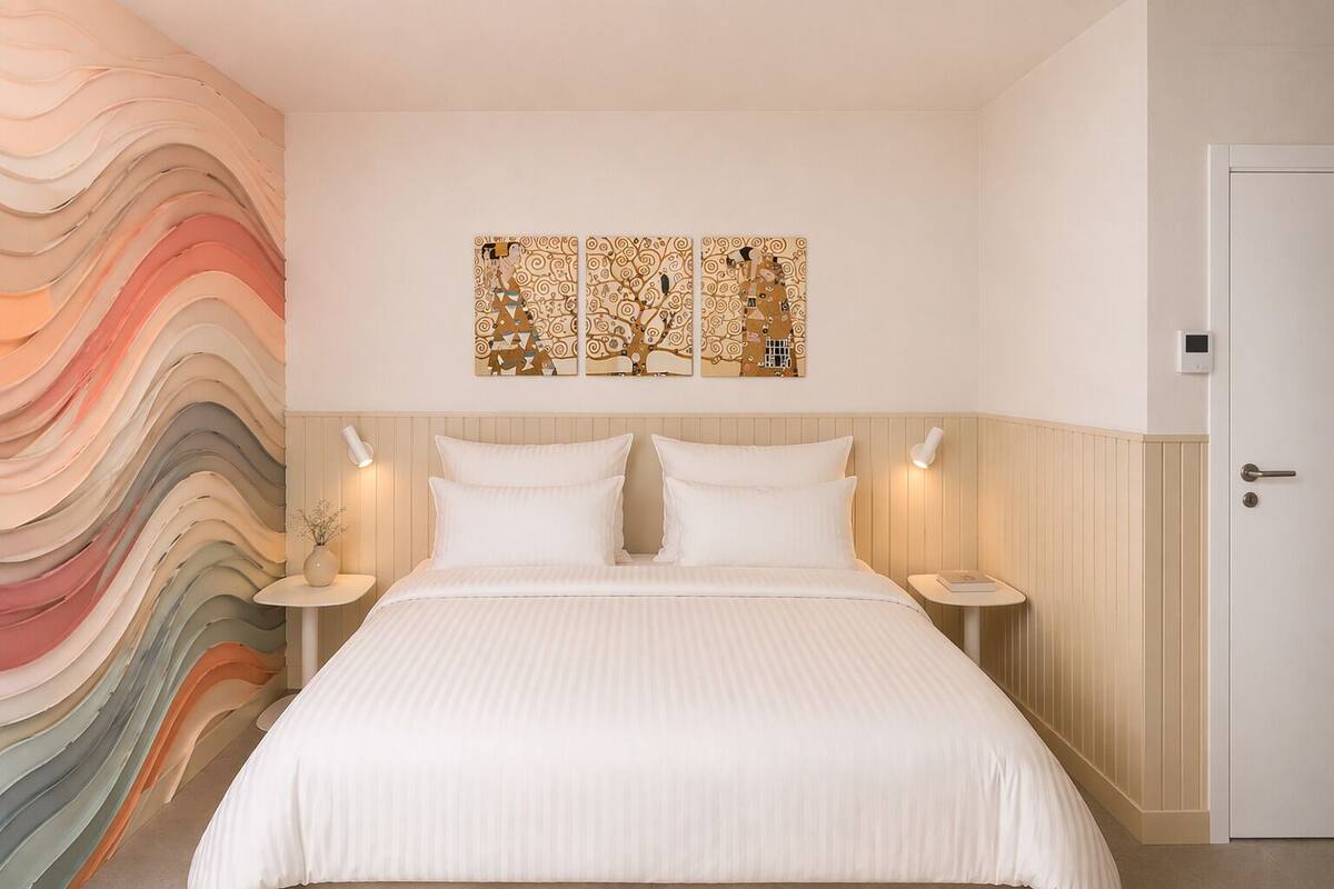 Une chambre à coucher comprenant un lit, deux tables de chevet, une œuvre d’art murale et une porte.