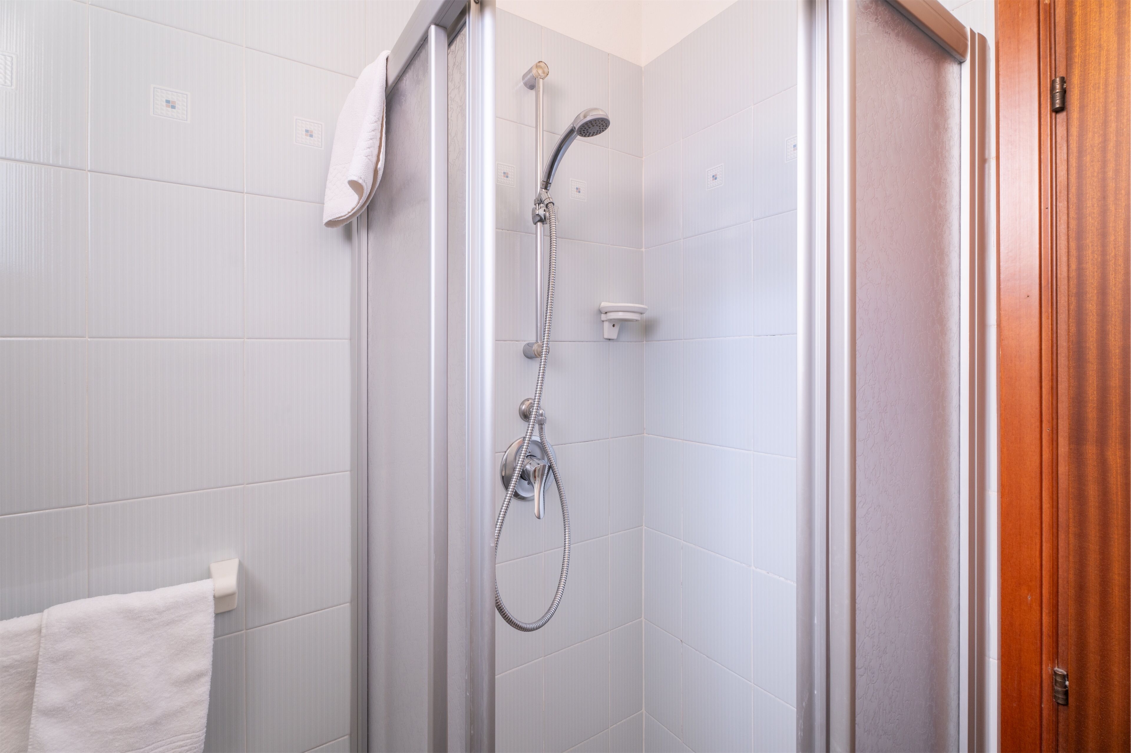 Ducha con cabezal de ducha de mano y panel de control en la pared.