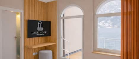 A hotel room with a bed, a mounted sign, a window with a view, and a door.