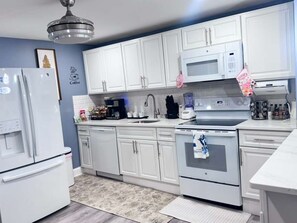 A modern kitchen with white cabinets, a microwave, a stove, and a refrigerator. - Where Luxury and Convenience Converge (Scranton)
