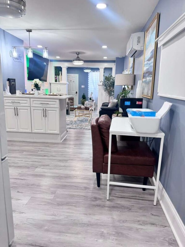 A modern kitchen with white cabinets, a dining area with a brown leather chair, and a white table. - Where Luxury and Convenience Converge (Scranton)