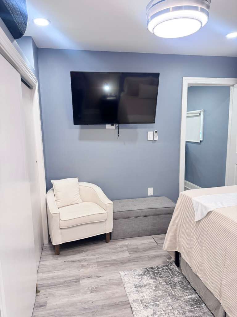 Une chambre à coucher comprenant un lit, une chaise, un téléviseur fixé au mur et un petit escalier.