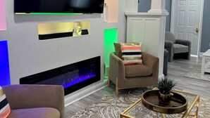 A modern living room with a flat-screen TV mounted on the wall, a fireplace, a comfortable sofa, a coffee table, and a ceiling fan. - Where Luxury and Convenience Converge (Scranton)