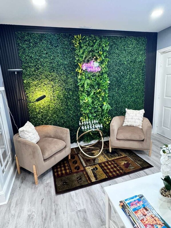A modern living room with two armchairs, a coffee table, a decorative wall with greenery, and a patterned rug. - Where Luxury and Convenience Converge (Scranton)