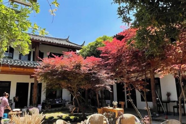 A traditional courtyard with a building, trees, and outdoor furniture. - Lijiang Shuhe K2 International Youth Hotle (Lijiang)