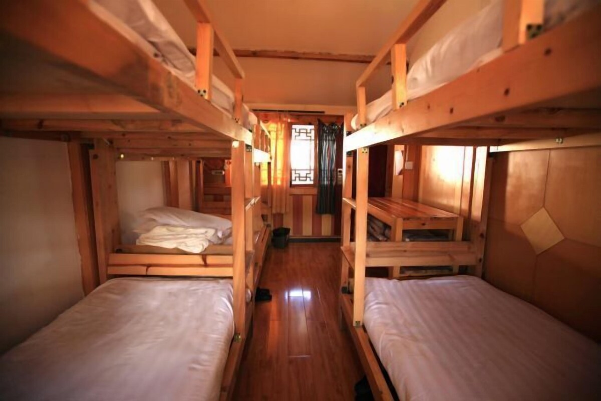Dormitorio con literas, paredes y suelo de madera.
