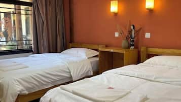 Habitación de hotel con dos camas individuales, cabeceros de madera y una ventana con cortinas.