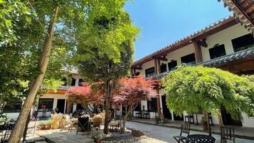 An outdoor courtyard with a dining area, seating, and potted plants.