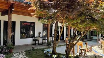 A courtyard with a stone pathway, wooden pergola, and seating area.