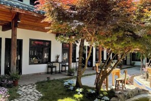 A courtyard with a stone pathway, wooden pergola, and seating area.