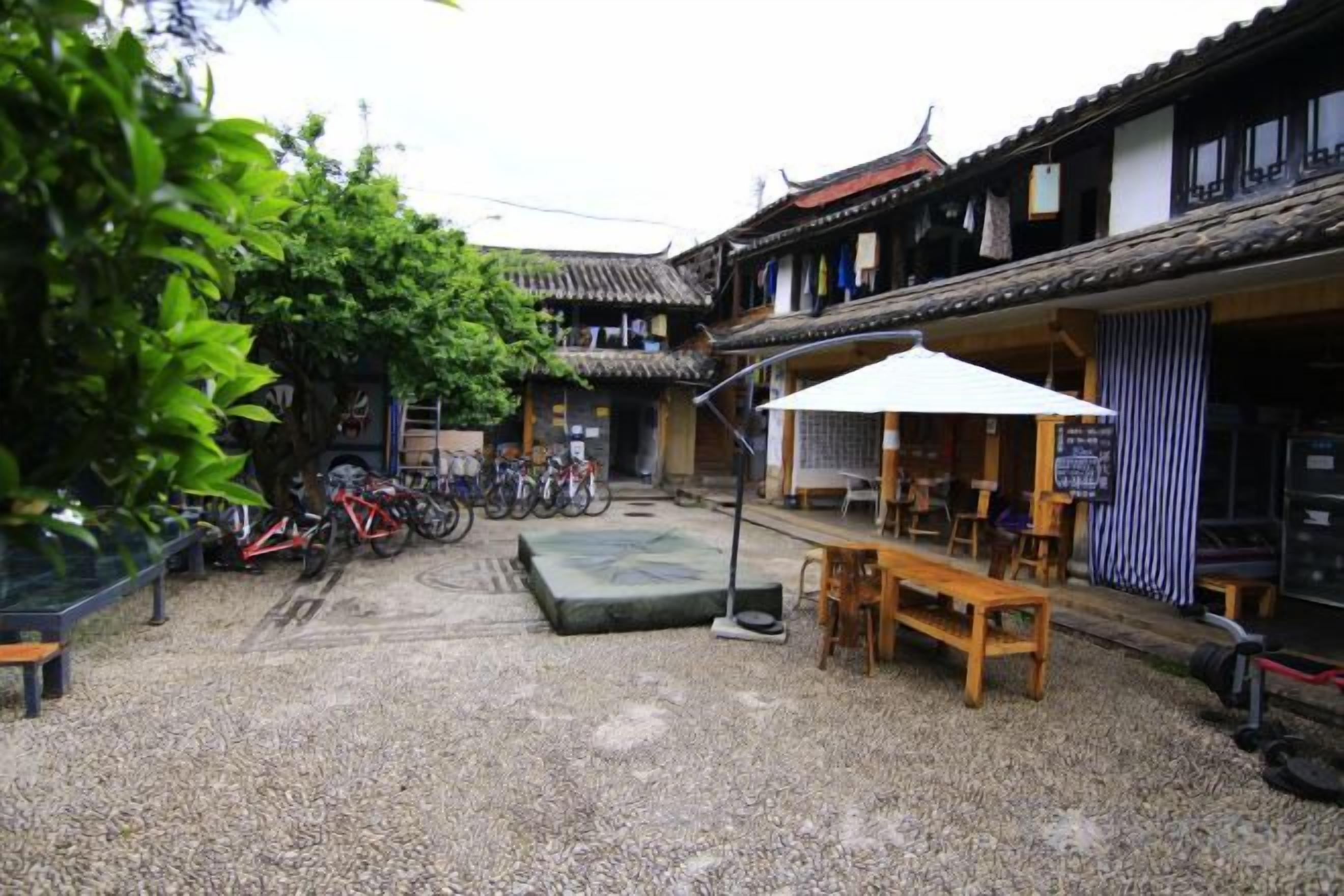 A courtyard with bicycles, a bench, and a table under a white umbrella.