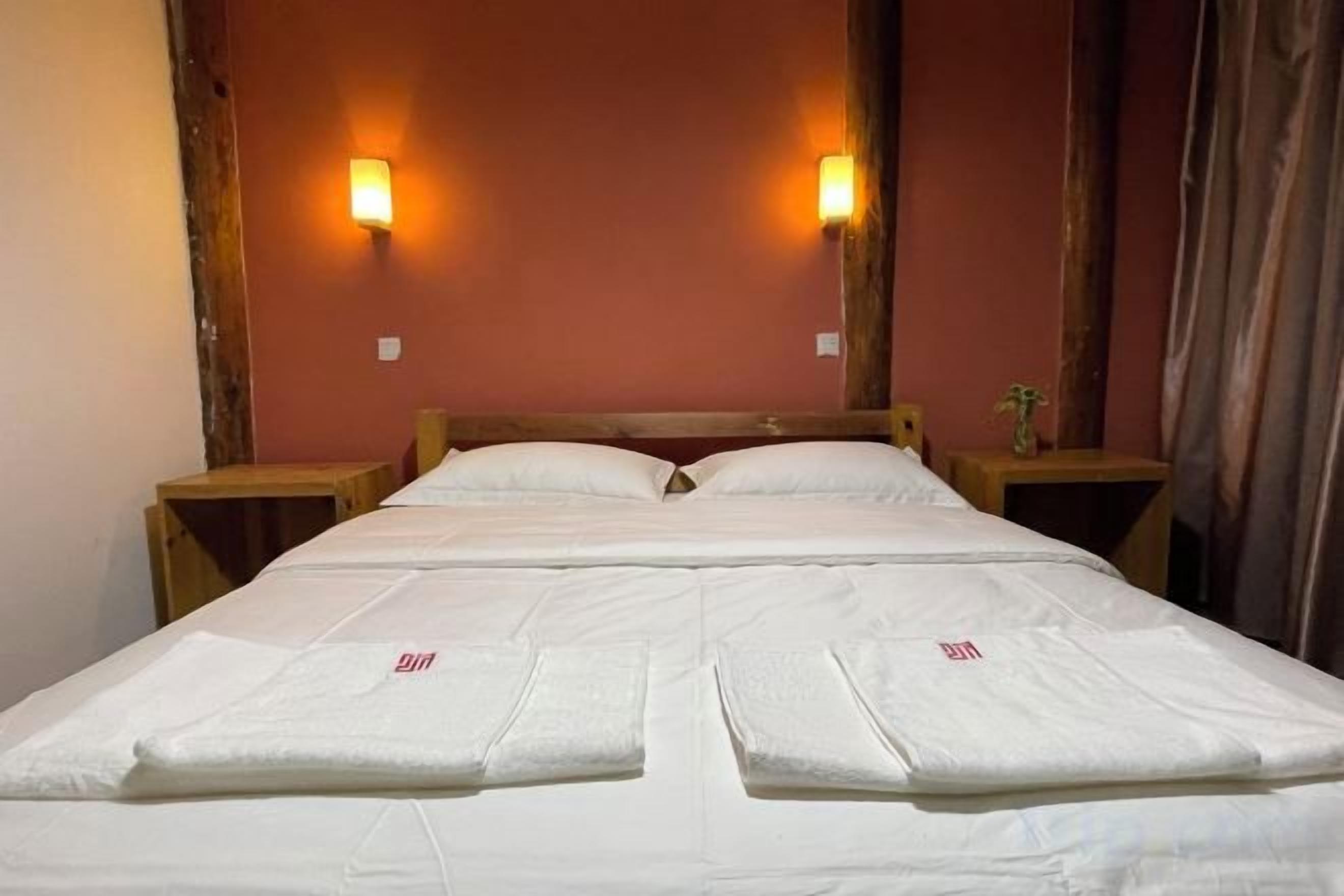 A double bed with a wooden headboard, two bedside tables, and wall-mounted lamps.