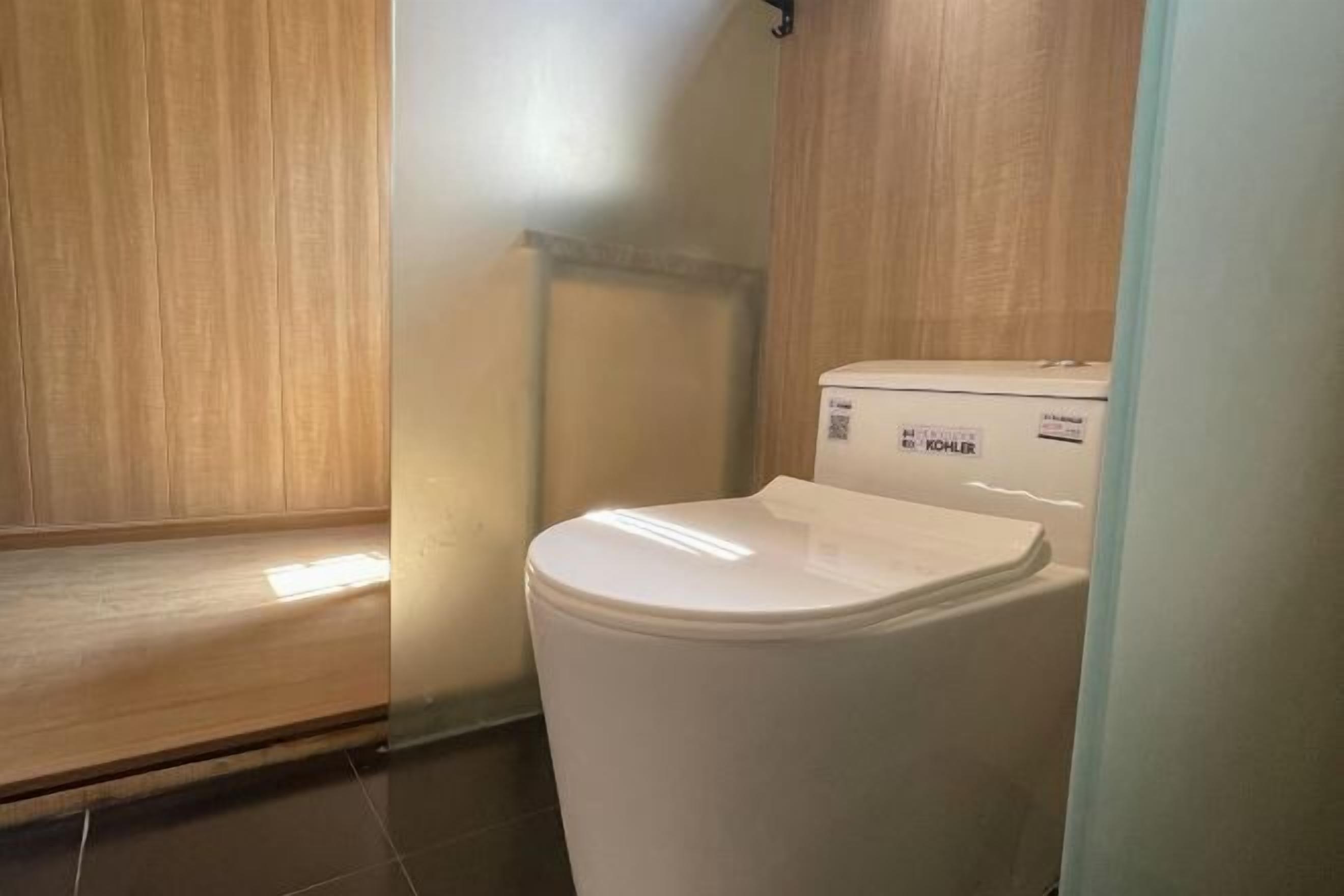 A white toilet in a bathroom with wooden paneling on the walls and a tiled floor.