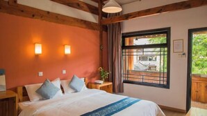 A bedroom with a large bed, wooden beams, a window with a view, and a nightstand with a lamp. - Lijiang Shuhe K2 International Youth Hotle (Lijiang)
