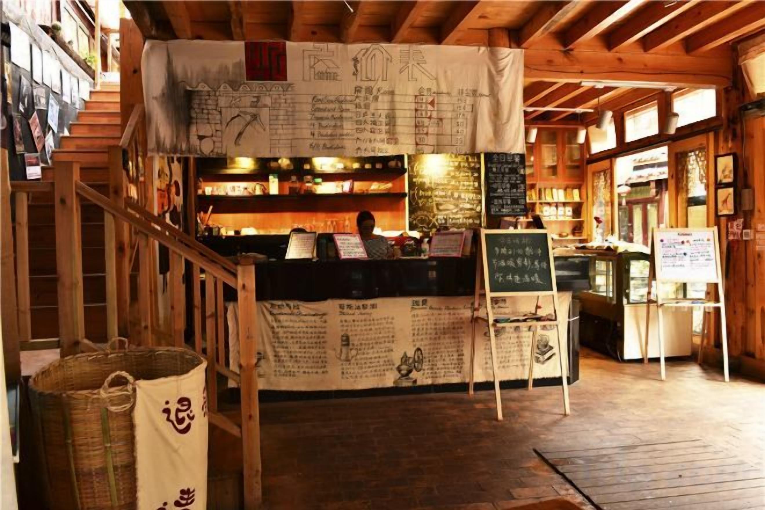 Interior de un restaurante con mostrador, paneles de menú y una escalera.