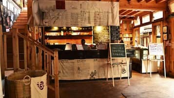 Interior de un restaurante con mostrador, paneles de menú y una escalera.