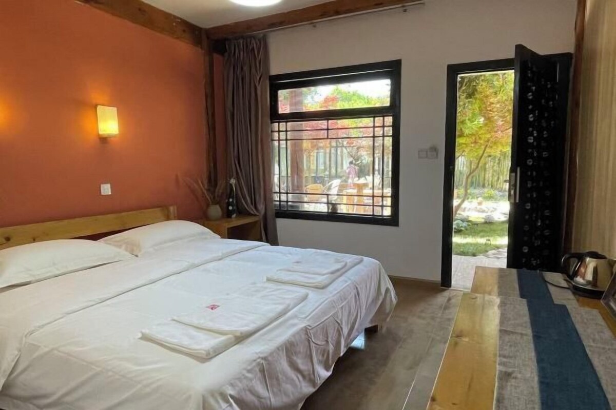 Un dormitorio con cama, ventana con vistas al exterior y puerta que da a un balcón.